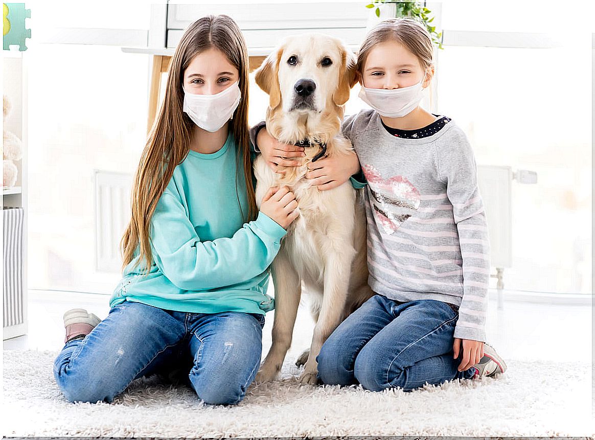 Girls with masks hugging a dog.